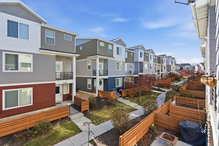 Modern townhome exterior featuring multi-toned siding, private balconies with metal railings, and individual fenced patios