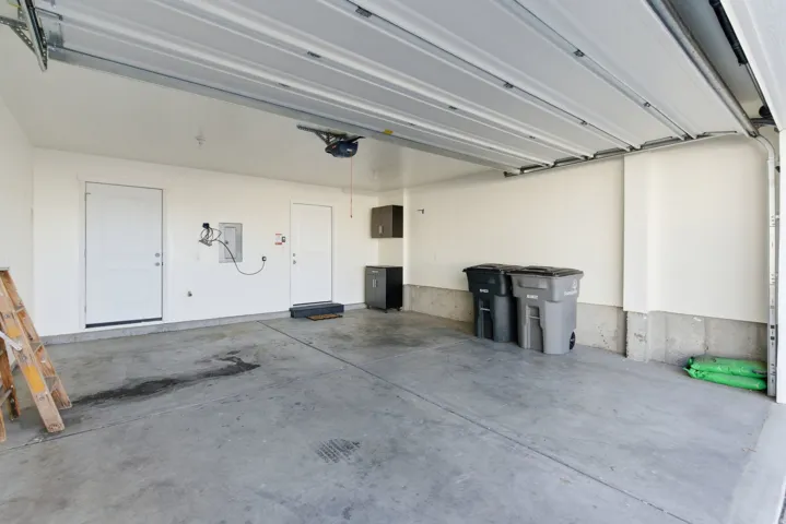 Attached garage with concrete flooring, two access doors, and an overhead garage door