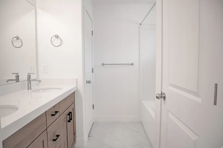 Primary bath with double sinks, large linen closet, and garden tub with shower