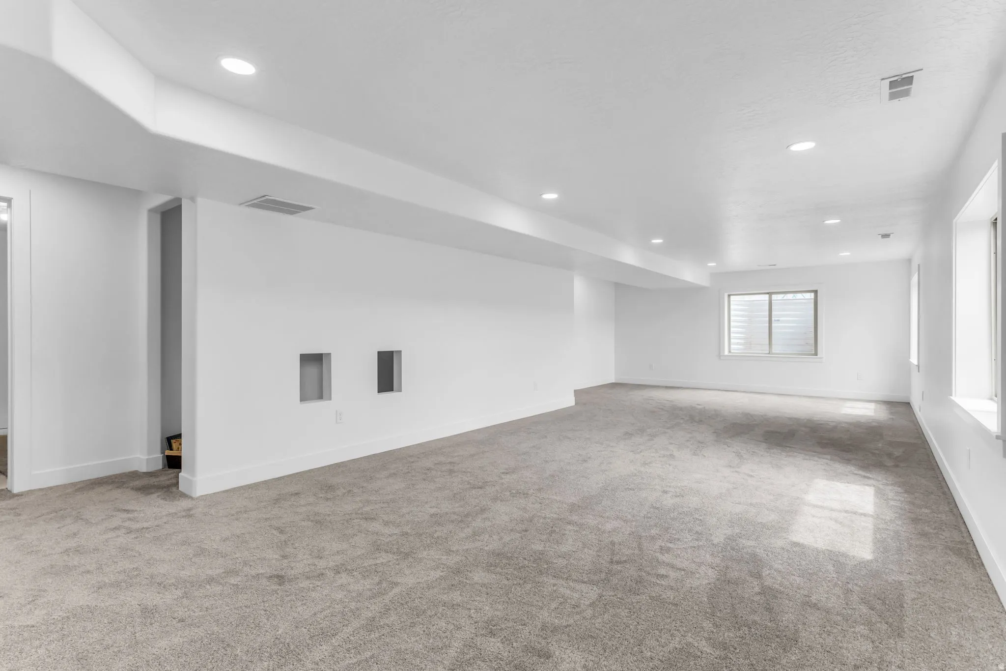 Expansive room with neutral carpeting, recessed lighting, and multiple windows