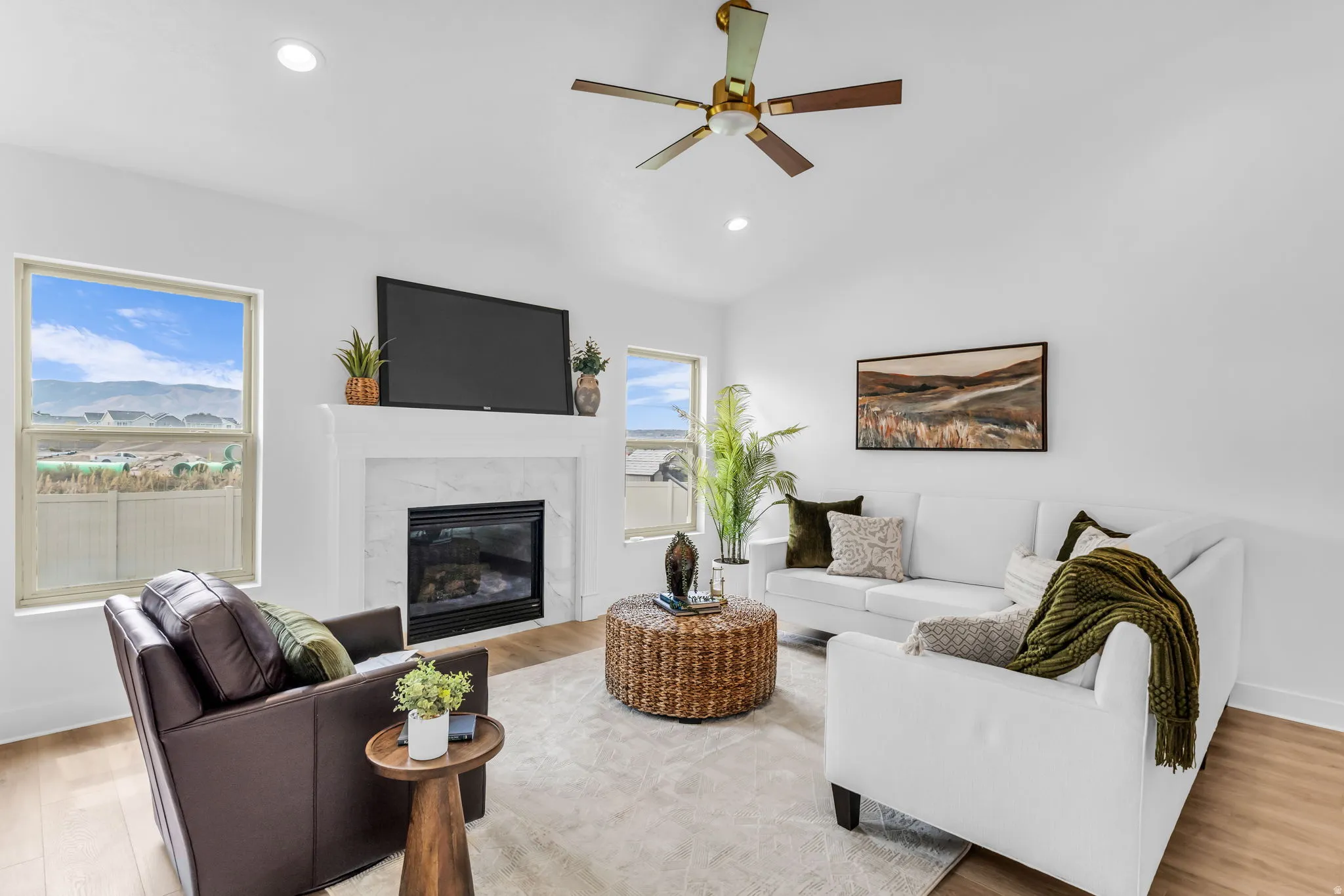 Living area featuring a gas fireplace with a stone surround, a white mantel, and wood-finish flooring