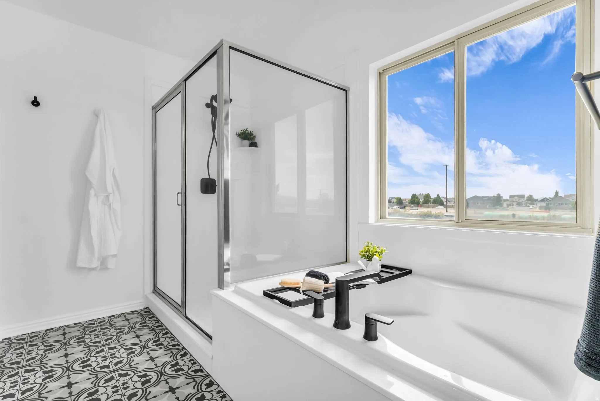 Soaking tub with matte black fixtures, walk-in shower with sliding glass door, patterned floor tiles, and a large window