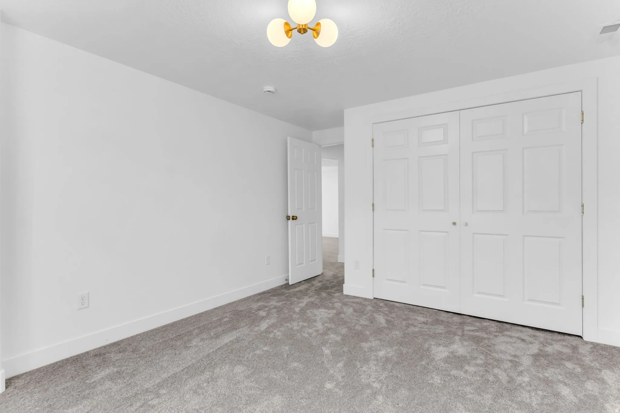 Plush carpeting, paneled bi-fold closet doors, and a decorative ceiling light fixture