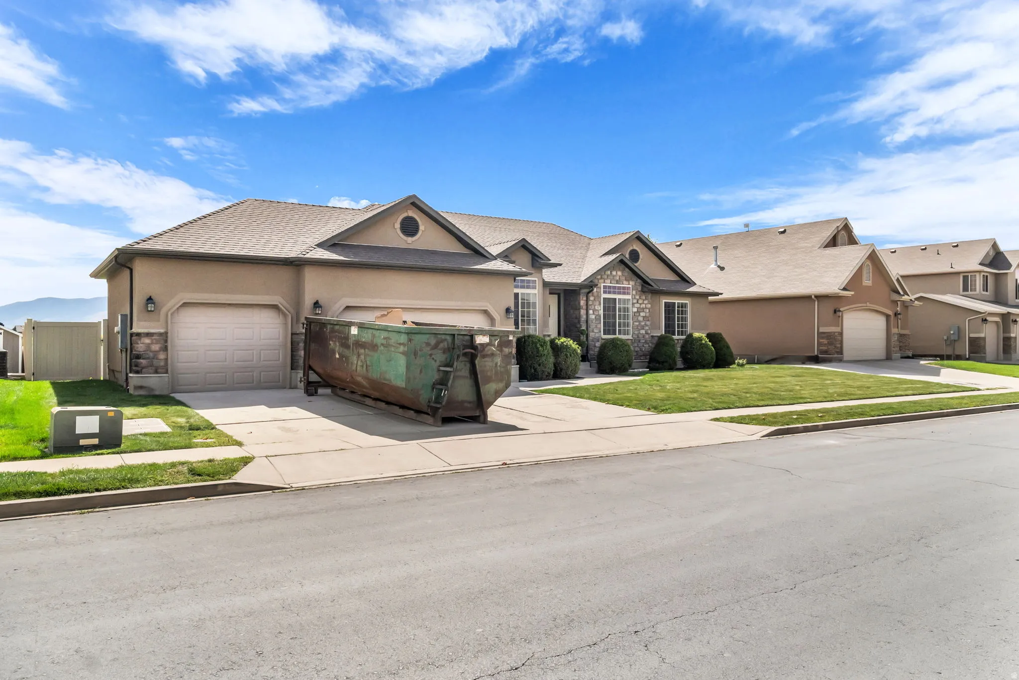 Stucco exterior with stone accents, two-car garage, and established front landscaping