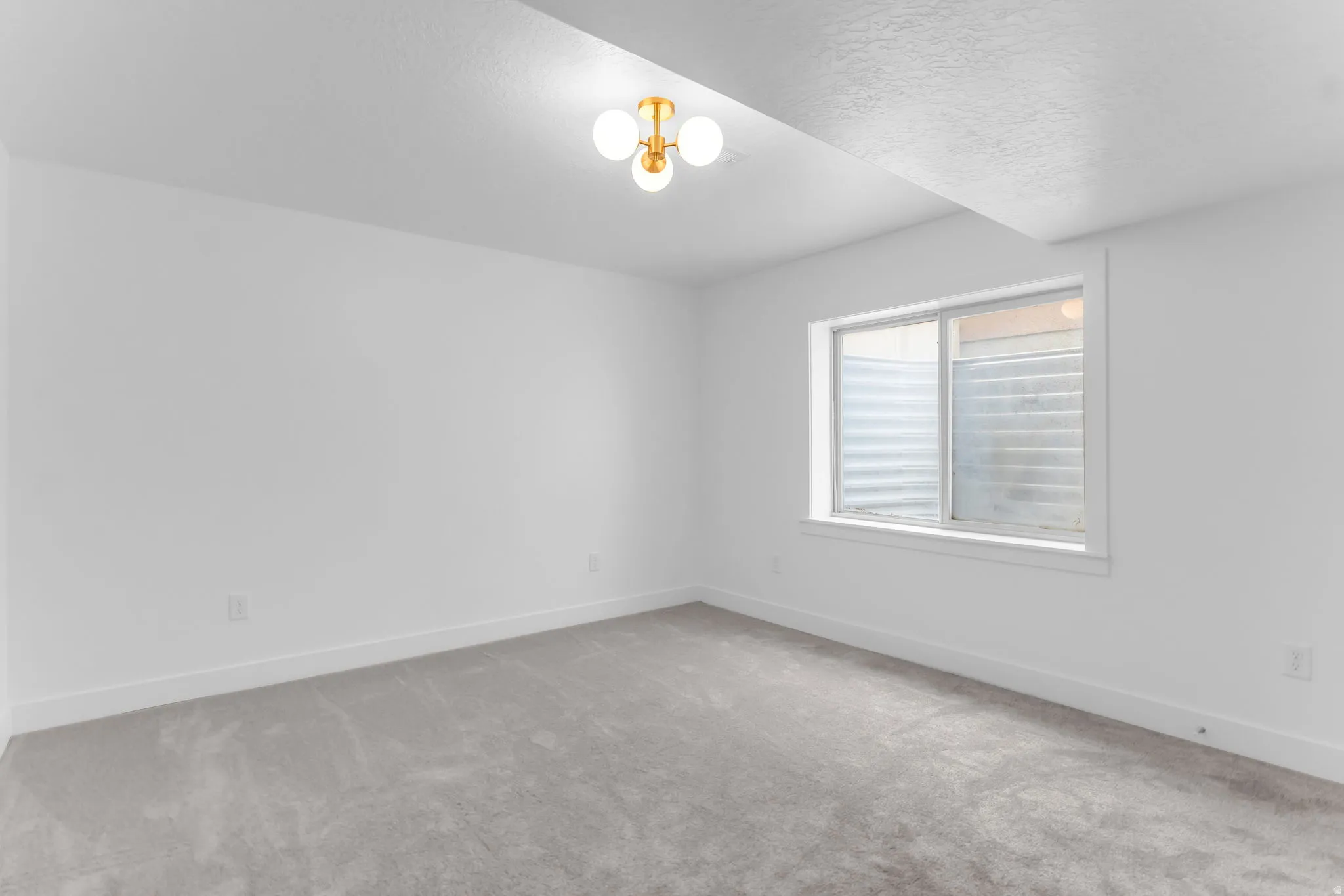 Neutral wall paint, light gray carpeting, and a contemporary ceiling light fixture
