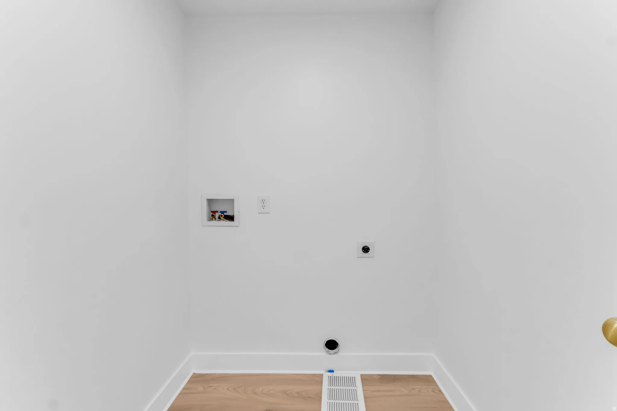 Dedicated laundry space featuring light wood-finish flooring and white walls