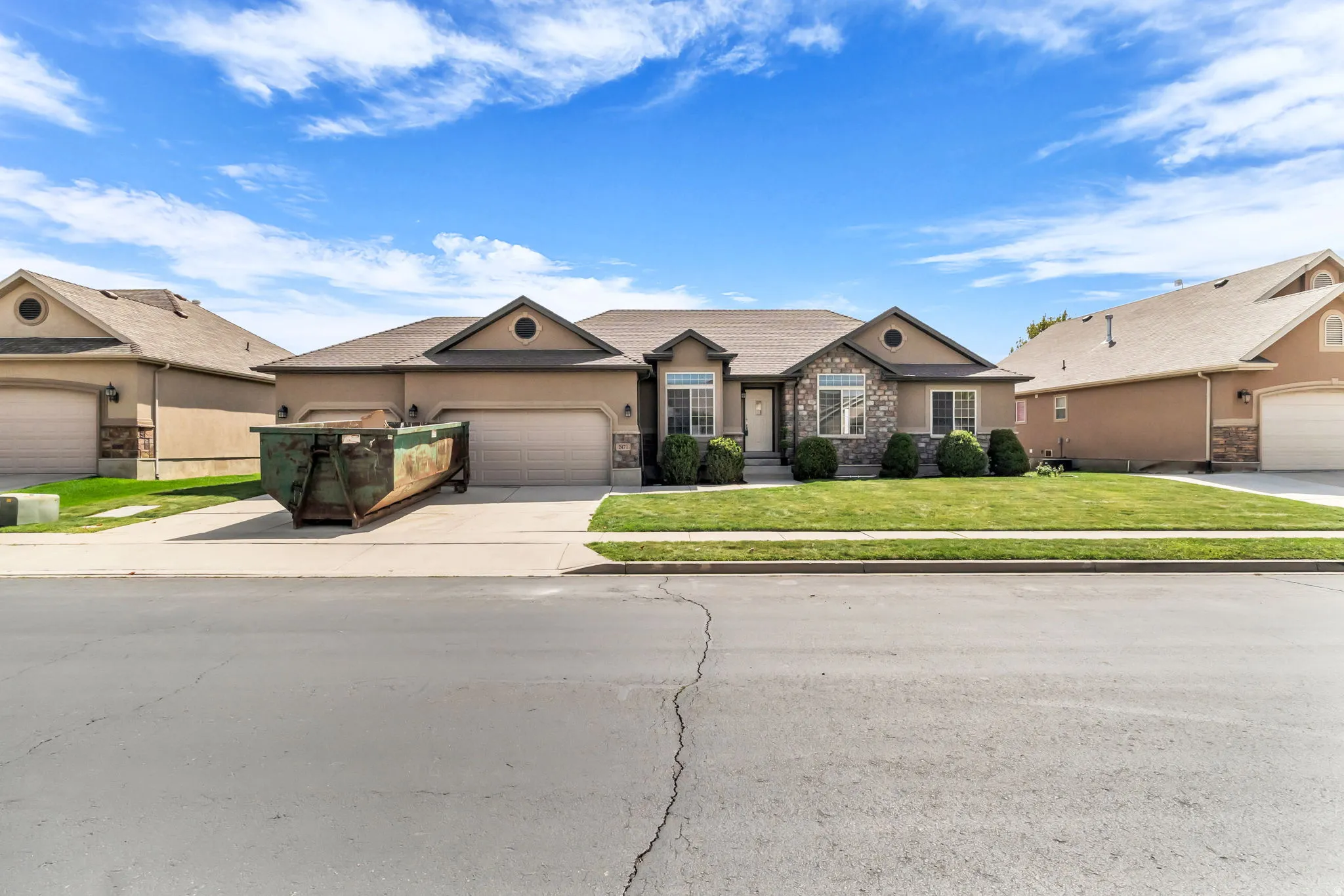 Stucco exterior with stone accents, attached garage, and a landscaped front yard with established shrubbery