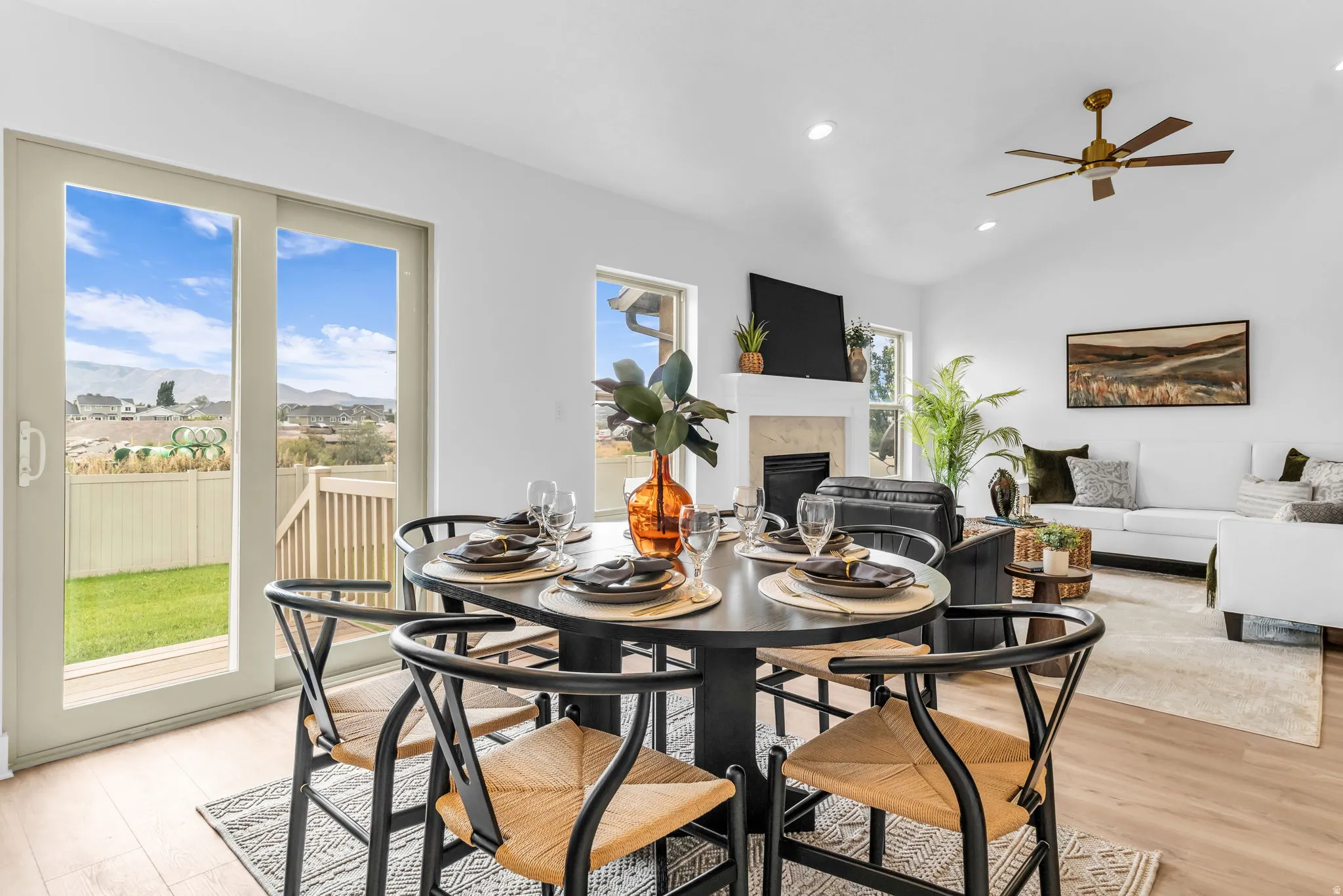 Open-concept living area with wood-finish flooring, vaulted ceilings, and a ceiling fan