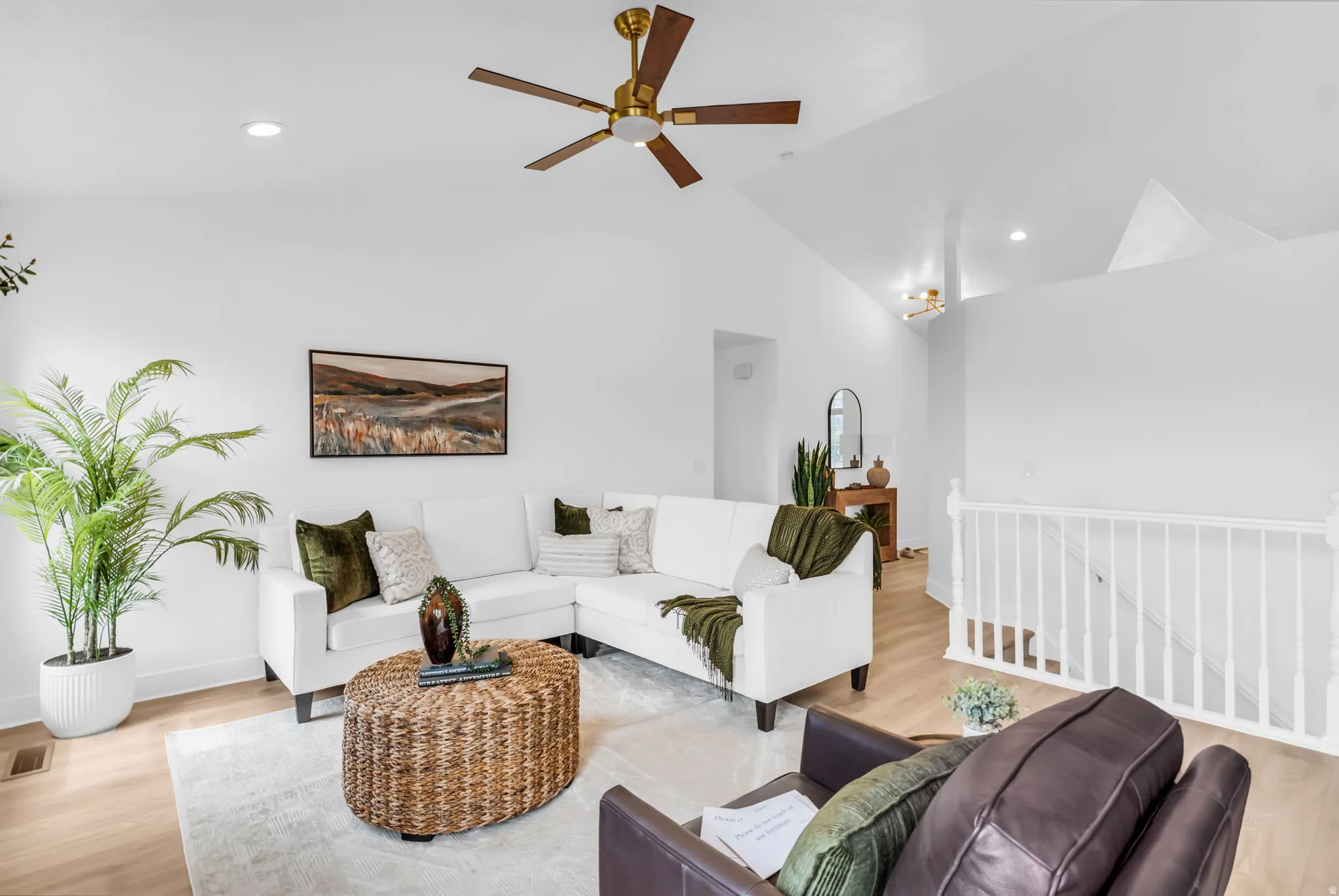 Vaulted ceilings with recessed lighting, wood-finish flooring, white wall tones, and a ceiling fan with brass accents
