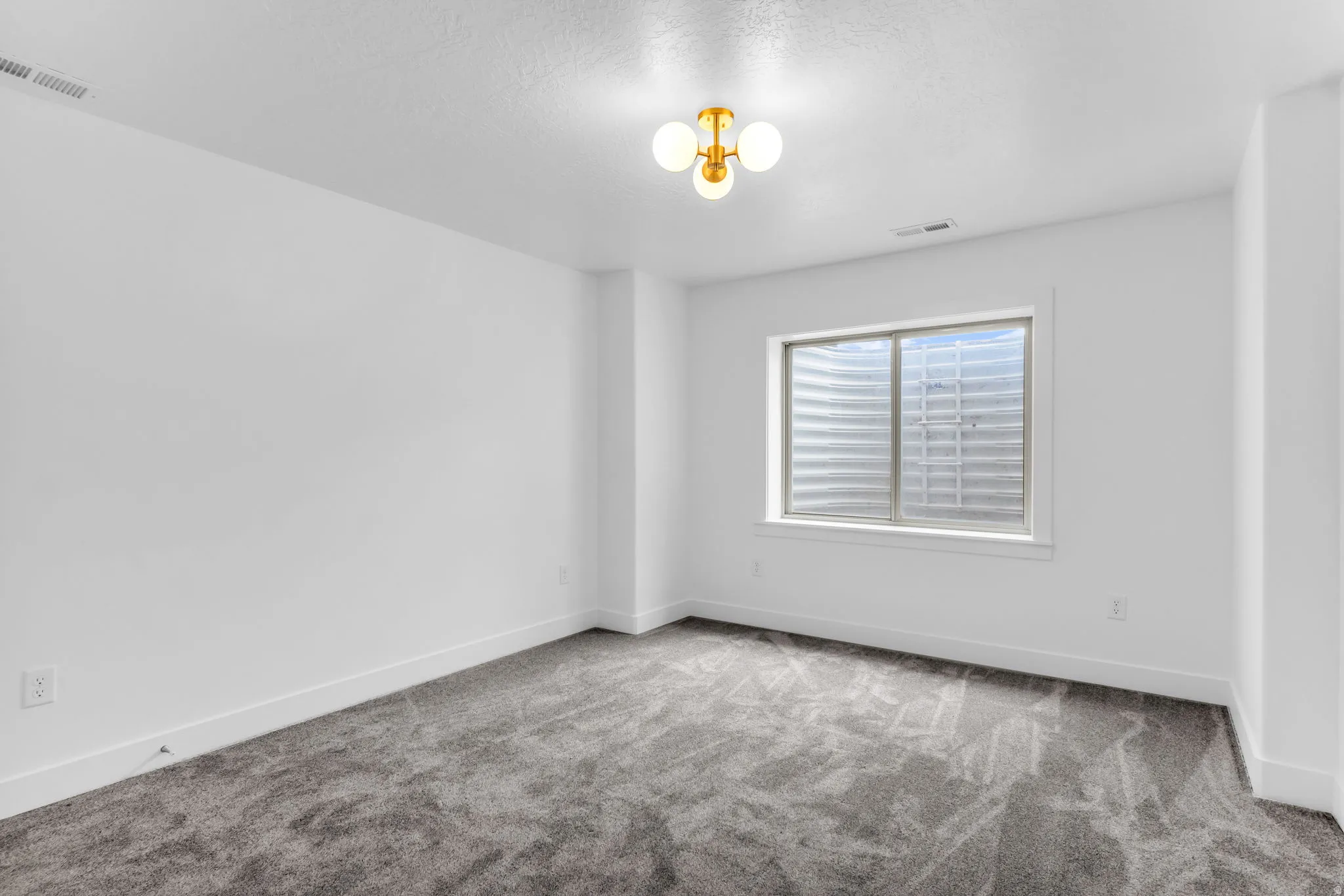 Recessed window with white trim, gray carpet, and a modern three-light ceiling fixture