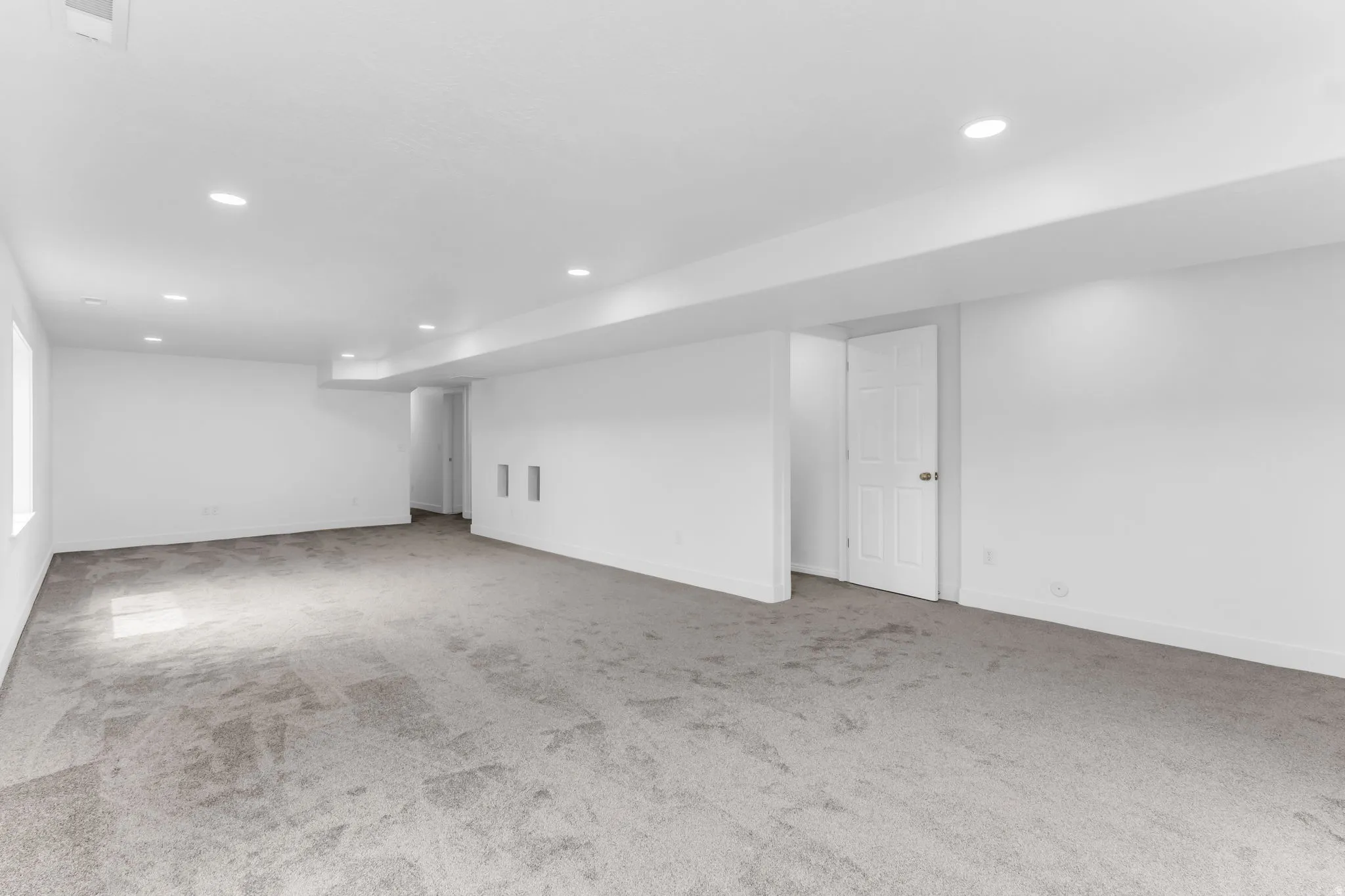 Expansive carpeted room featuring recessed lighting, white walls, and a window