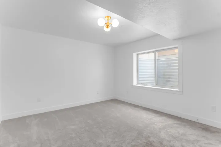 Neutral wall paint, light gray carpeting, and a contemporary ceiling light fixture