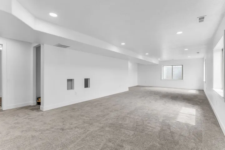 Expansive room with neutral carpeting, recessed lighting, and multiple windows