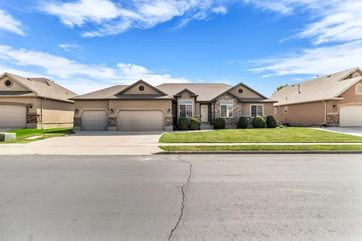 Stucco exterior with stone accents, mature landscaping, a two-car garage, and an additional single-car garage