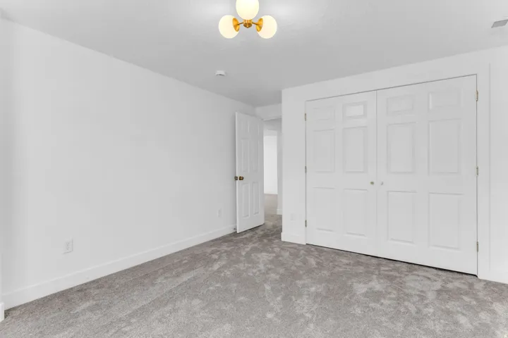 Plush carpeting, paneled bi-fold closet doors, and a decorative ceiling light fixture