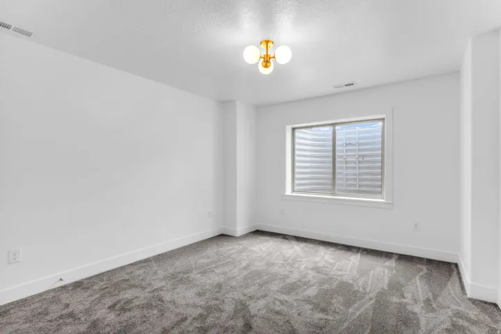 Recessed window with white trim, gray carpet, and a modern three-light ceiling fixture