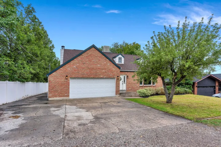 Red brick exterior with a white garage door, gabled roofline, and dormer window