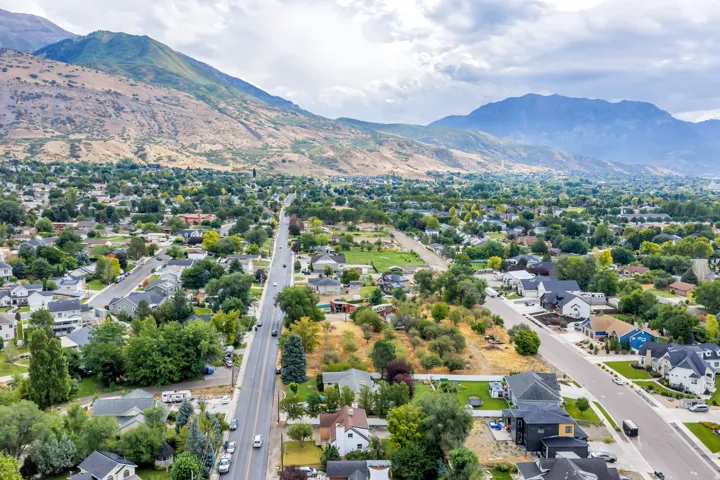 Expansive residential area featuring established homes, mature trees, paved streets, and mountainous terrain