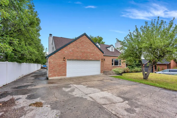 Brick exterior with a white garage door, dormer windows, and an established front yard