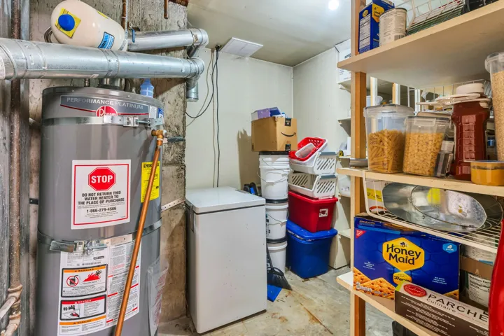 Utility area featuring a water heater, exposed ductwork, and built-in shelving