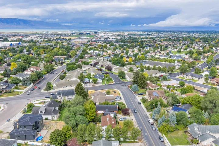Expansive neighborhood with mature trees, residential properties, and paved roadways, set against a distant mountain range