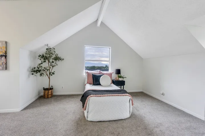 Vaulted ceiling with an exposed beam, neutral wall paint, single window, and carpeted flooring