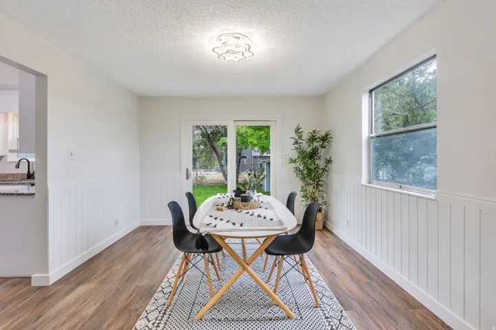 Wood-finish flooring, white wainscoting, sliding glass door, recessed lighting, and a single-pane window