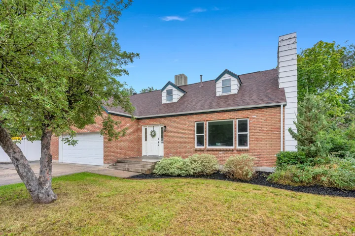 Brick exterior with a dormered roofline, prominent chimney, and an attached garage