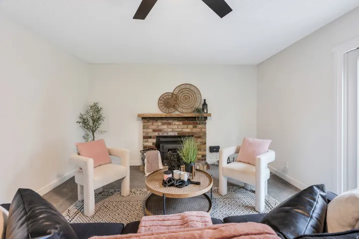 Brick fireplace with a wood mantel, ceiling fan, and light wall finishes