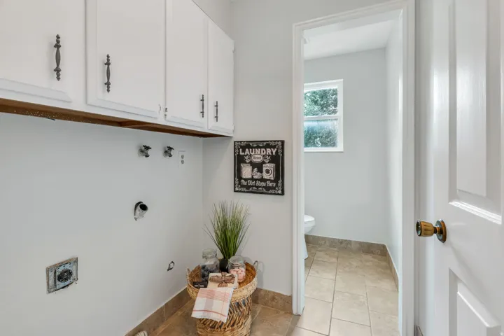 White upper cabinetry with dark hardware and tile flooring