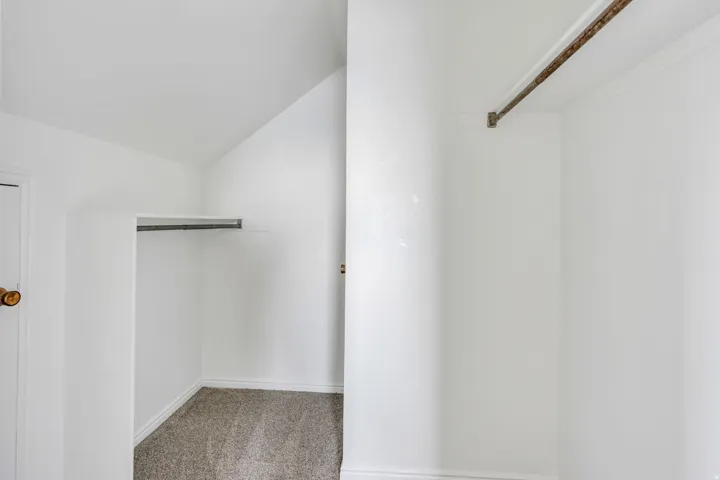 Carpeted closet with built-in hanging rod and a secondary hanging rod installation