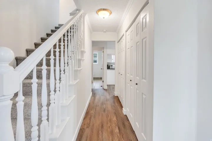 Carpeted staircase with white balusters, wood-finish flooring, white paneled bi-fold closet doors, and recessed ceiling lighting