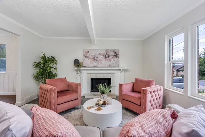 Fireplace with stone surround and classic mantel, wood-finish flooring, white trim, and multiple windows