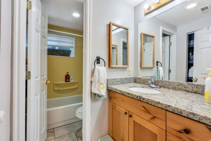 Bathroom vanity with a granite countertop, undermount sink, and wood-finish cabinetry