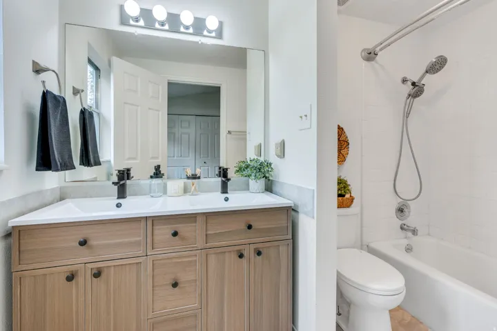 Dual vanity with white undermount sinks, wood-finish cabinetry, and matte black plumbing fixtures