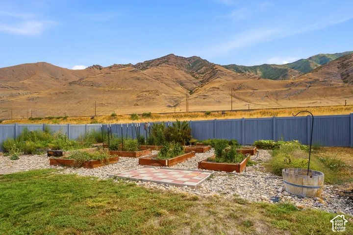Expansive backyard with multiple raised garden beds, a gravel ground cover, a patterned paver patio, and a privacy fence
