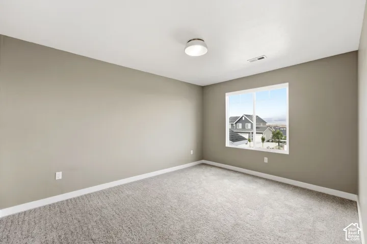 Neutral tone wall finish with light-colored carpeting, a contemporary flush mount ceiling light, and a large window