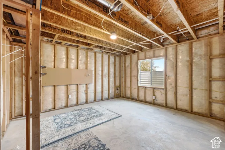 Unfinished space featuring wood framing, exposed ceiling joists, insulation, and a window