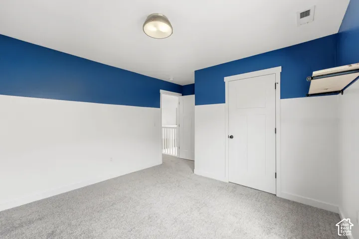 Plush gray carpeting, two-tone wall paint, white trim work, white interior doors, and a ceiling-mounted light fixture