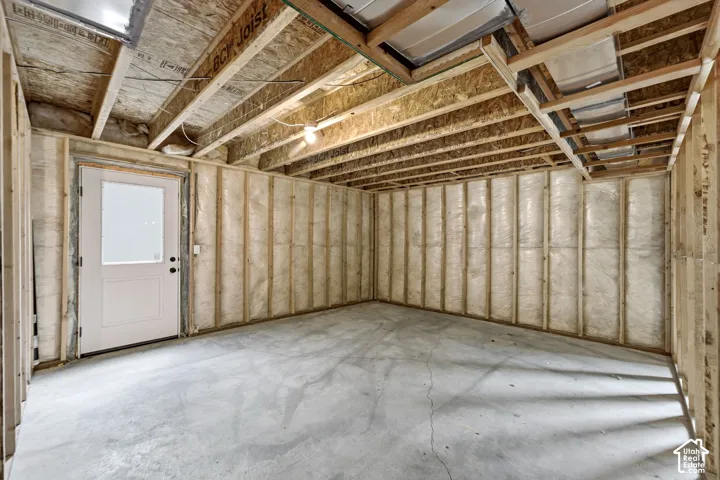 Spacious interior featuring exposed beam ceiling structure with insulation, concrete flooring, and stud-framed walls ready for finishing