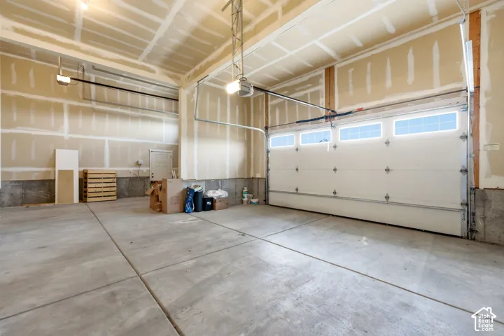Concrete floor garage with overhead lighting, a single garage door with upper-level windows, and an automated garage door opener