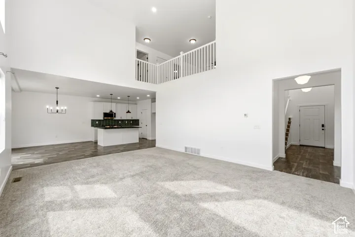 Vaulted ceilings, open concept design, kitchen island with pendant lighting, wood-finish flooring, and white painted balusters