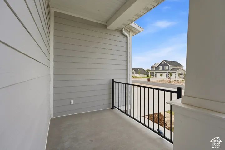 Covered porch with concrete flooring, vertical columns, and black metal railings
