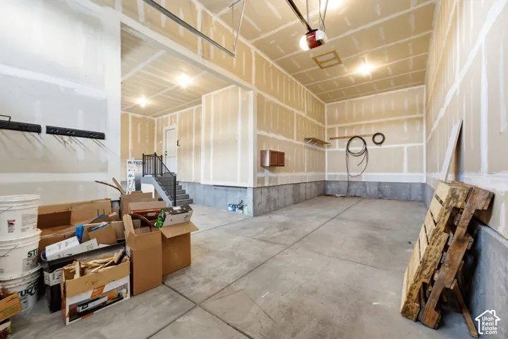 Spacious garage with concrete flooring, exposed drywall, overhead lighting, and an automatic garage door opener