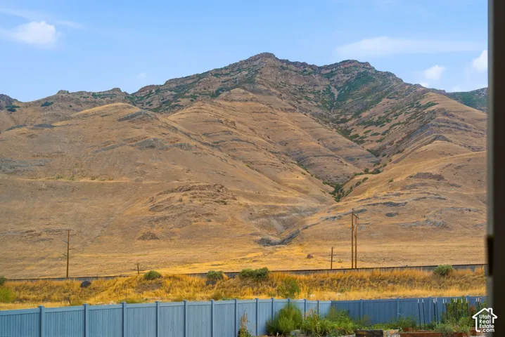 Dramatic mountain backdrop with expansive open terrain, utility infrastructure, and native vegetation framing the property