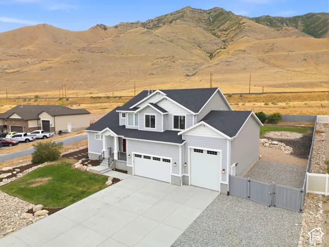 Two-story residence with light gray siding, dark shingle roof, and a concrete driveway
