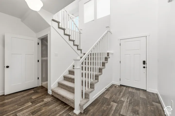 Entryway featuring wood-finish flooring, a carpeted staircase with white railings, and a multi-panel door