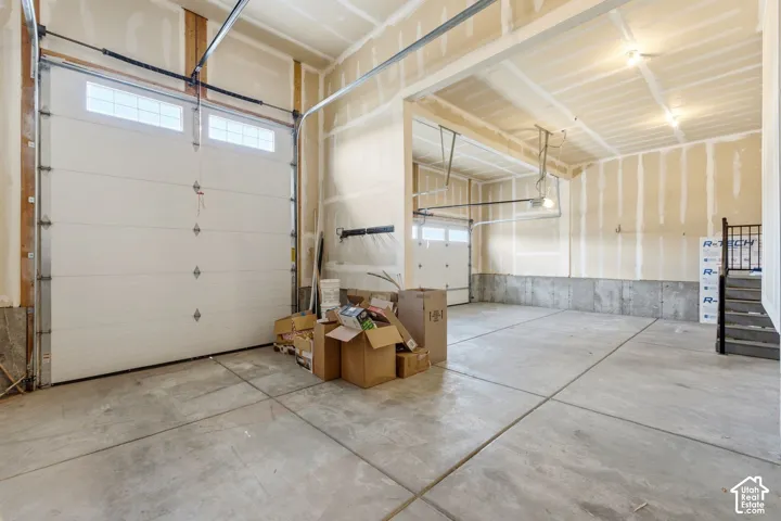 Spacious garage with exposed framing, concrete flooring, and multiple overhead doors with transom window accents