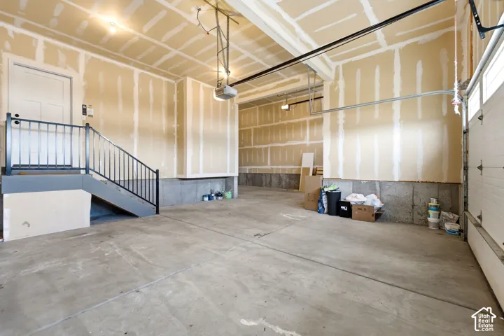 Concrete flooring garage with an interior access door, a built-in staircase, and a garage door opener