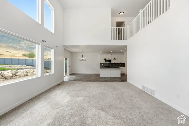 Two-story great room with high ceilings, multiple windows, and light gray carpeting